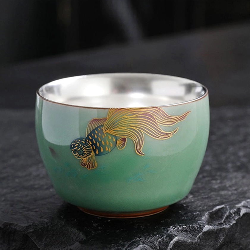 Fancy golden koi fish motif celadon tea cup with silver inner wall displaying traditional Buddhist prosperity symbol