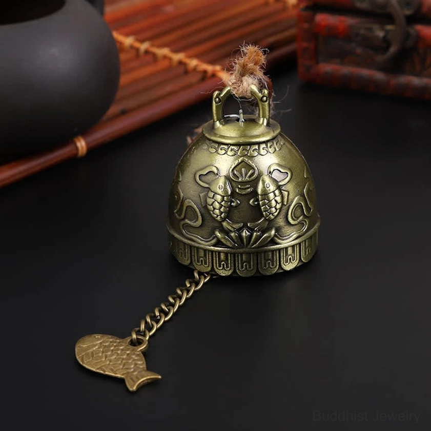Double koi carved Buddhist wind chime with embossed fish pattern on black vintage display