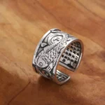 Koi fish heart sutra carved copper ring, 3/4 side view showing detailed fish carving and inner sutra text on adjustable open band