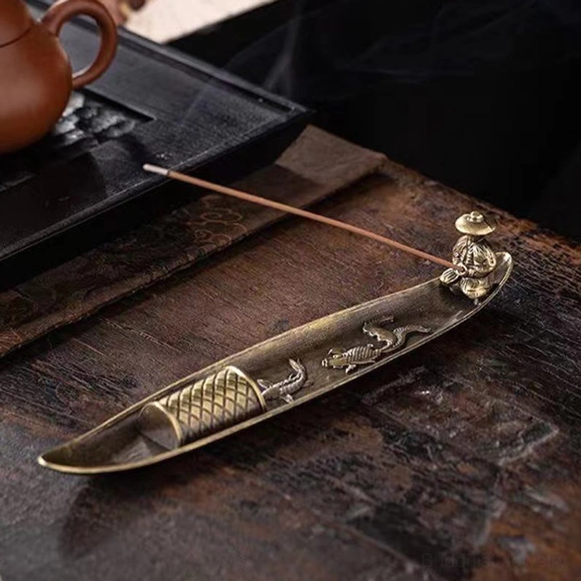 Overhead flat lay view of koi fish incense burner on tea ceremony table, bronze metal with embossed fish motifs