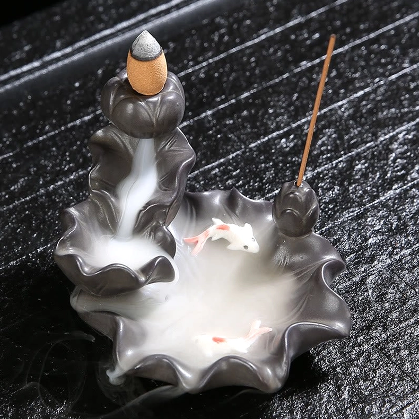 Top view of ceramic koi fish incense holder with backflow cone and stick incense on striped wooden tray