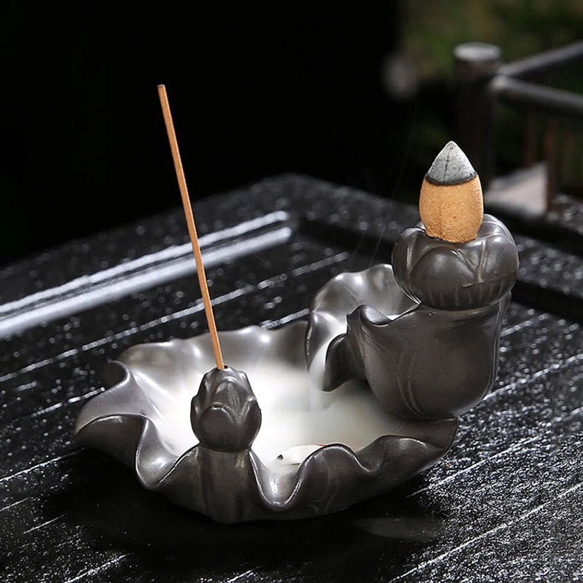 Side view of handcrafted ceramic koi fish incense burner with lotus base on outdoor wooden terrace