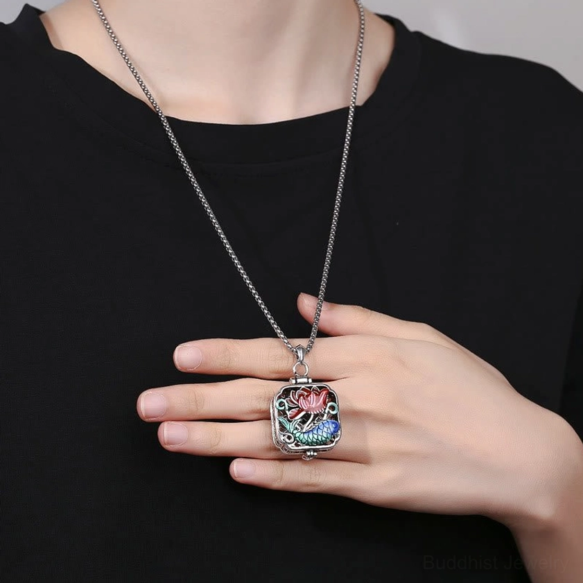 Koi fish lotus necklace pendant worn on body - silver chain draped on black clothing showing styling and length