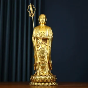 Ksitigarbha Bodhisattva copper statue full frontal view with polished gold finish, lotus pedestal, and dharma staff on wooden table