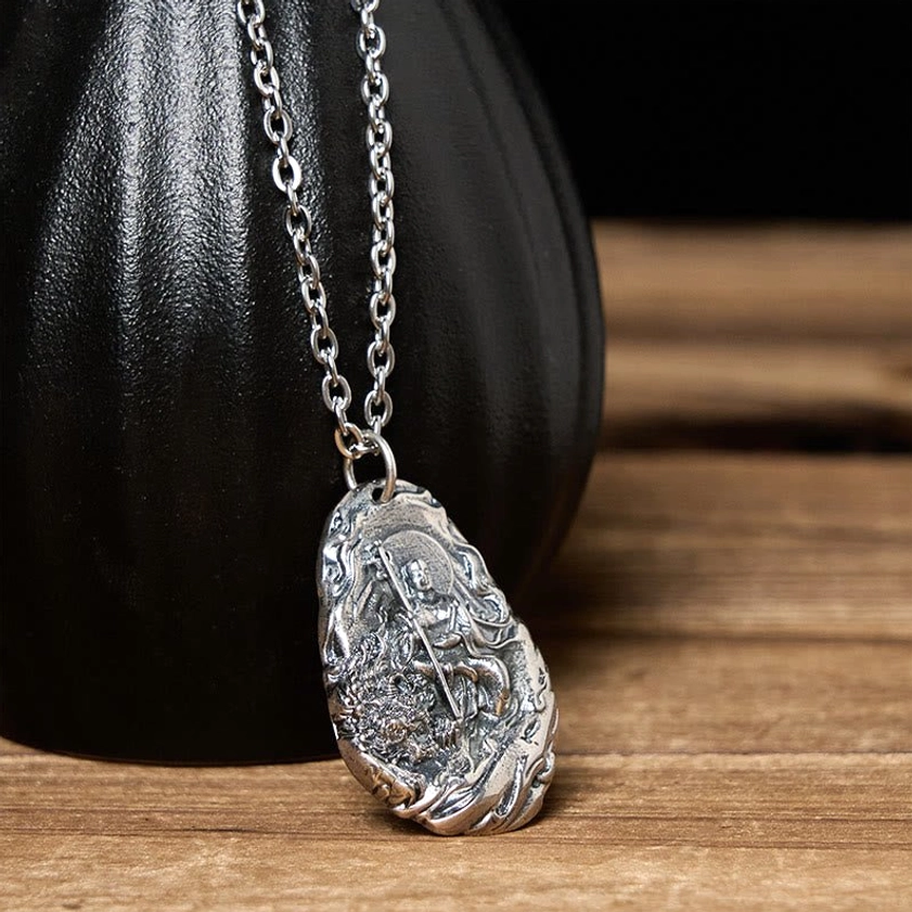 Ksitigarbha Bodhisattva pendant necklace with aged silver texture and guardian staff design, dark ceramic vessel background