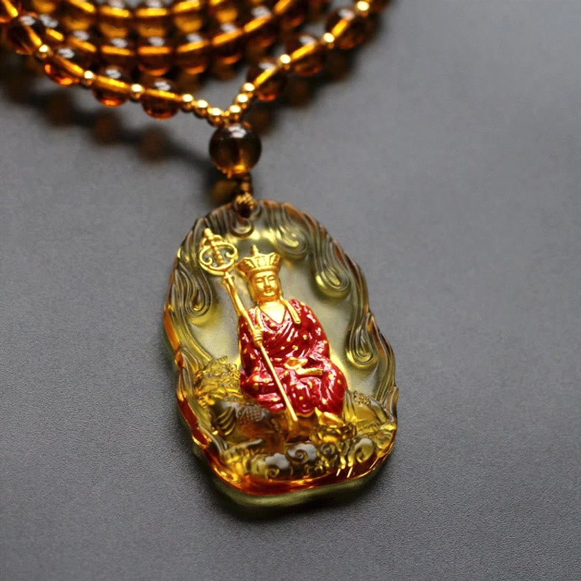 Amber liuli glass Ksitigarbha Buddha pendant with flame texture frame, seated red Buddha figure with khakkhara, oblique close-up