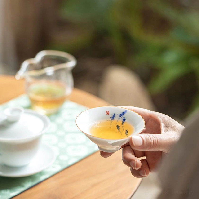 Close-up kung fu tea ceremony with fish-patterned Buddhist teacup holding brewed tea