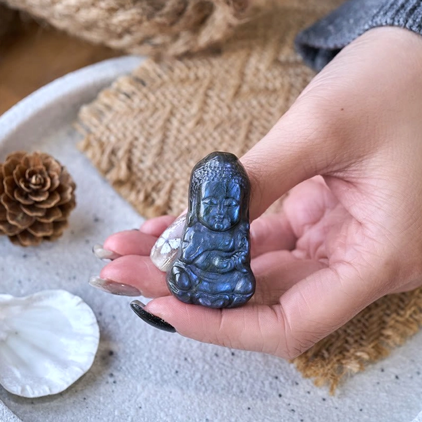 Hand holding mini labradorite Buddha figurine showing scale and polished stone texture