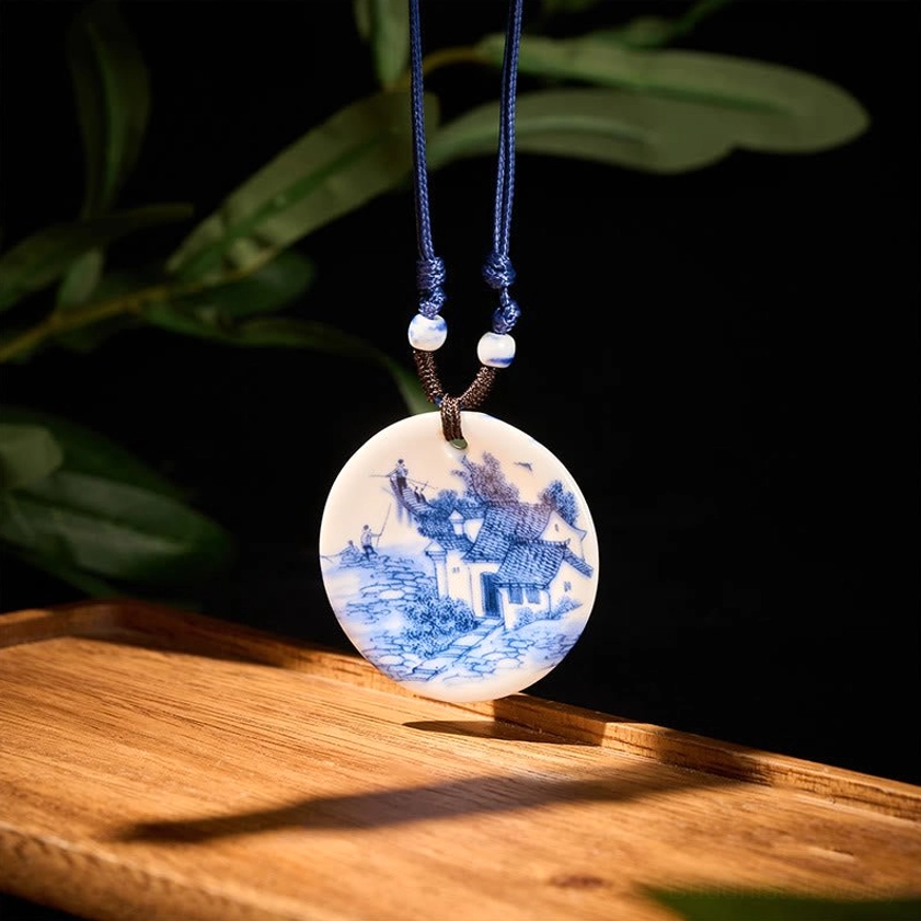 Buddhist ceramic pendant necklace showing detailed hand-painted landscape design on front