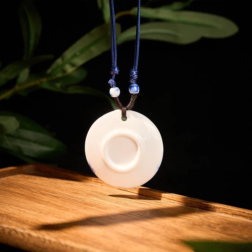Landscape ceramic pendant necklace hanging view displaying scenic village design on dark background