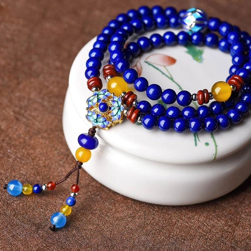 Multi-strand Buddhist mala bracelet set with Lapis Lazuli and Yellow Agate beads, displayed with enamel pendant tassel on decorative paper