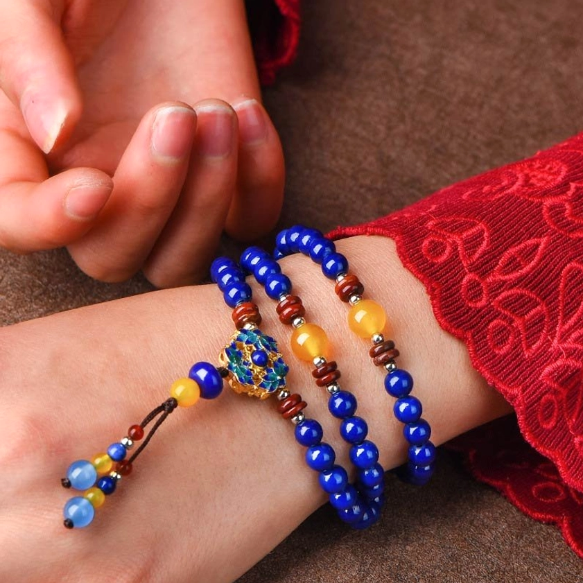 Buddhist mala bracelet with Lapis Lazuli beads worn on wrist with colorful tassel pendant, showing deep blue gemstone tones