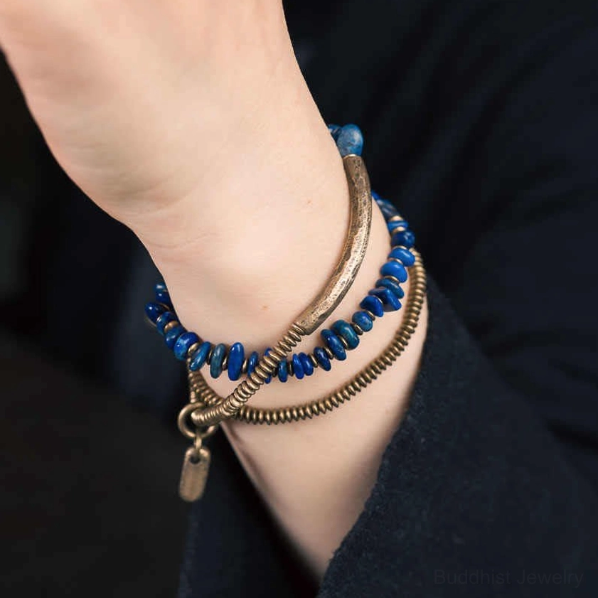 Real-life wearable lapis lazuli wrap bracelet on wrist with hanging bronze charm tag, showing actual wearing effect