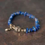 Lapis lazuli Buddhist bracelet with irregular chip beads and vintage metal toggle clasp, overhead flat lay view on dark wooden surface