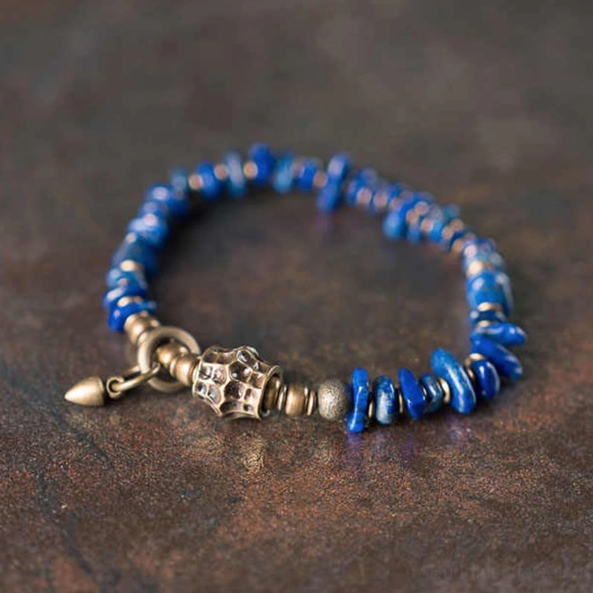 Lapis lazuli Buddhist bracelet with irregular chip beads and vintage metal toggle clasp, overhead flat lay view on dark wooden surface