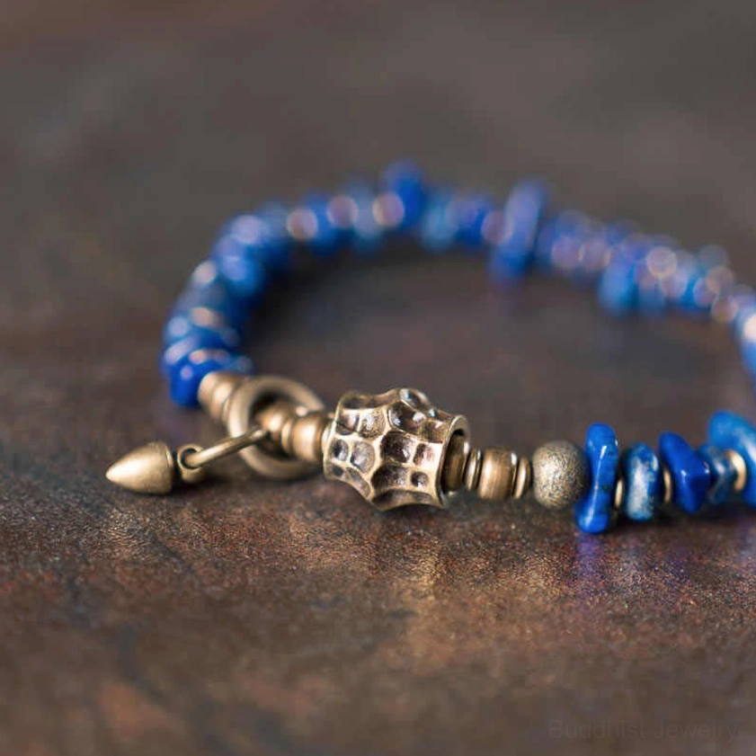 Detailed close-up of lapis lazuli Buddhist bracelet clasp and metal accents on dark brown wooden surface