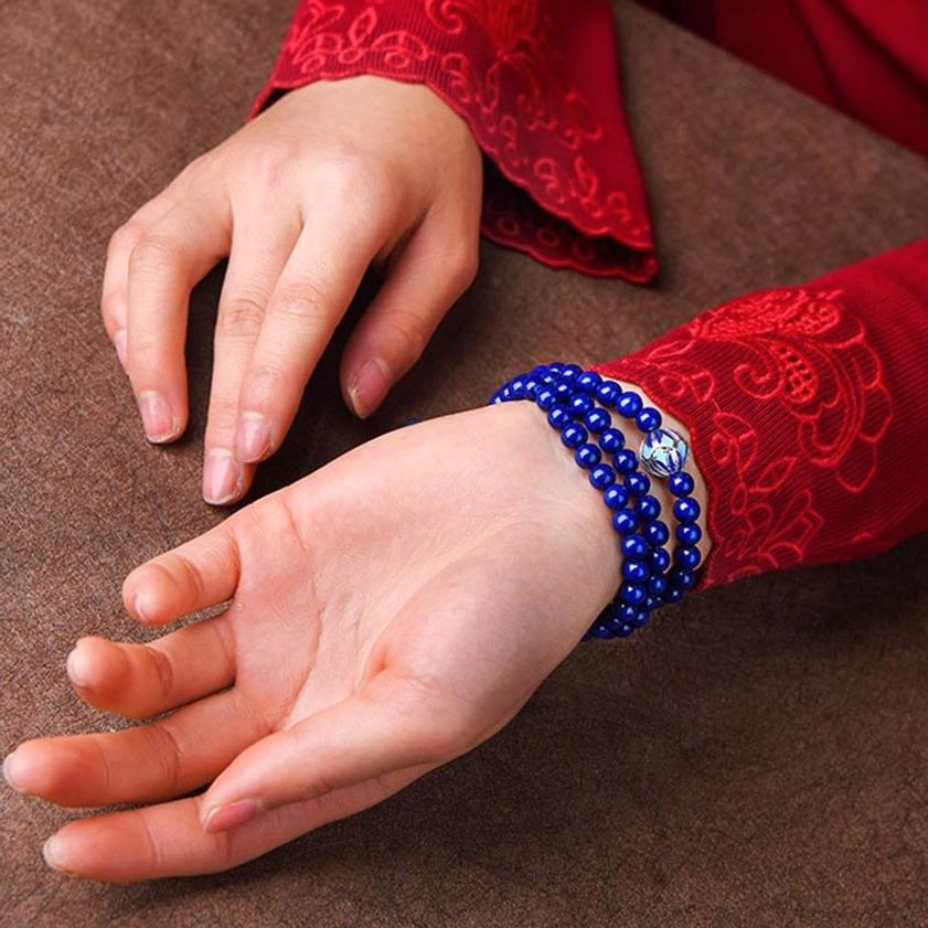 Single-wrap stackable Lapis Lazuli mala bracelet with blue enamel accents, worn on hand with traditional embroidered sleeve