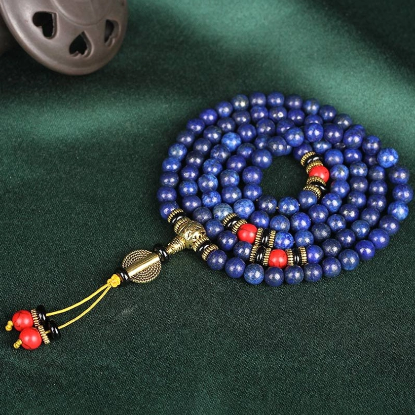 Fully coiled lapis lazuli 108 bead prayer mala with gold metal accessories and red decorative tassel pendant on dark background