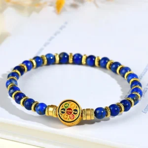 Lapis lazuli om mani padme hum bracelet with blue stone beads and gold accents on office desk