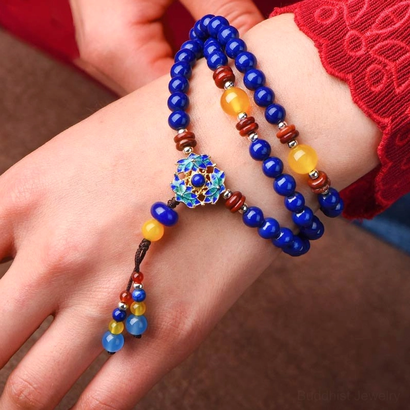 Handcrafted Lapis Lazuli and Yellow Agate mala bracelet worn on hand, featuring detailed blue enamel flower pendant with mixed accent beads