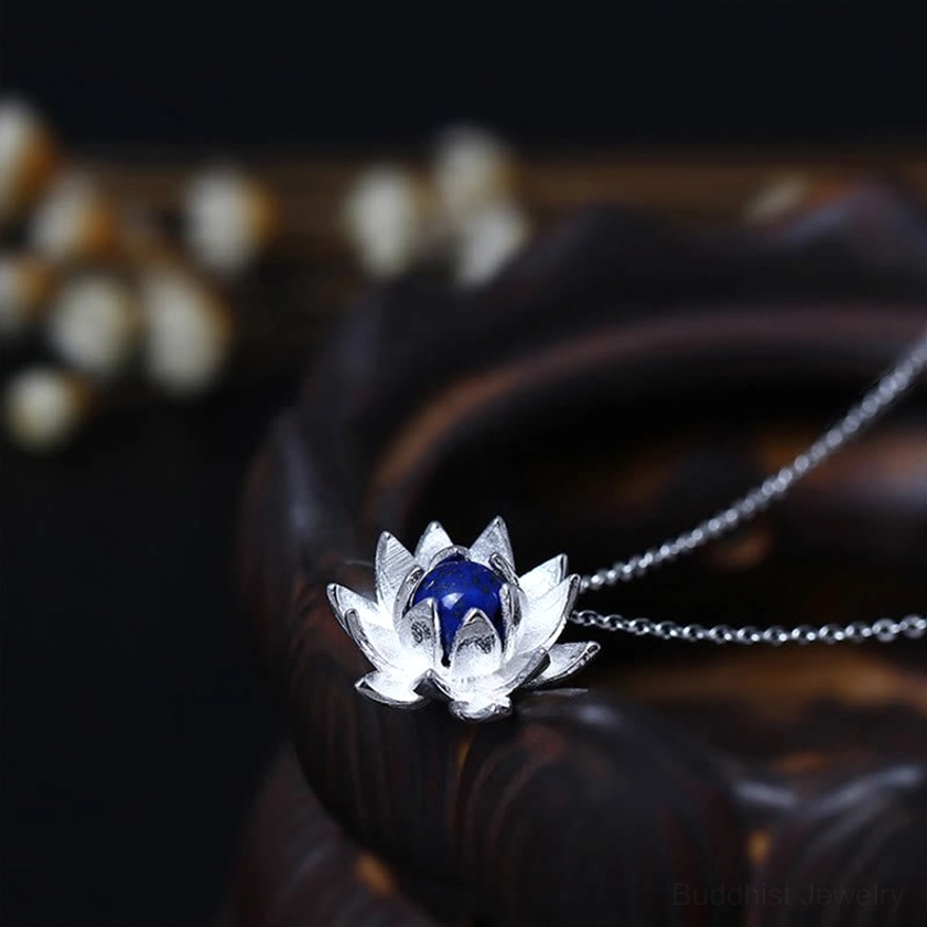 Lapis lazuli lotus flower sterling silver necklace pendant with 3D blooming design, deep blue gemstone center, displayed on wooden surface with dried flowers