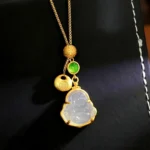 Laughing Buddha chalcedony copper necklace pendant with Fu character charm on black leather jewelry display box, showcasing gold-toned chain and green accent stone