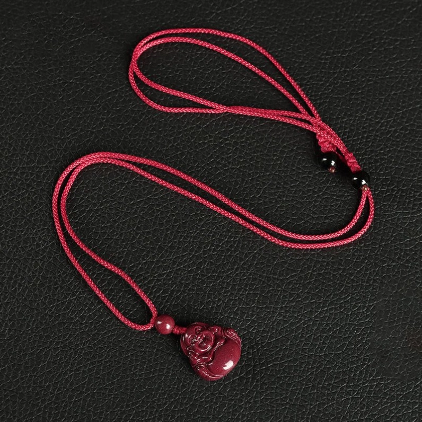 Bright red braided rope Laughing Buddha cinnabar necklace pendant with beaded accents on leather textured background