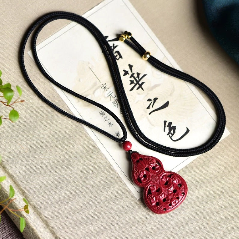 Cinnabar Buddhist necklace pendant with laughing Buddha carving close-up showing granular stone texture and details