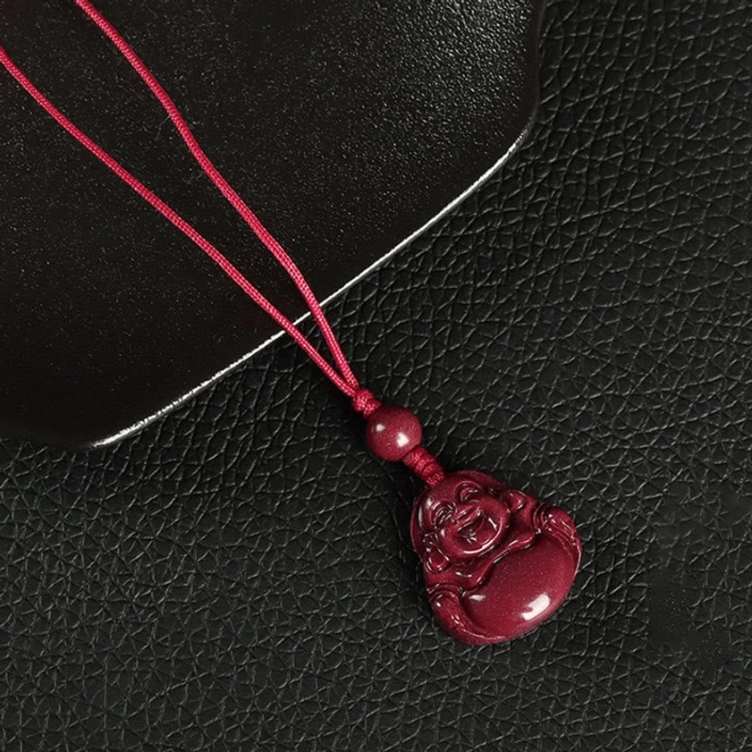 Bright red rope Laughing Buddha cinnabar phone lanyard with decorative spacer bead on leather background