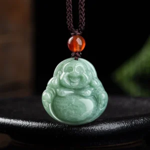 Laughing Buddha cyan jade pendant necklace displayed on black ceramic tray, showing front view with intricate carved smiling Buddha face