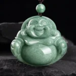 Laughing Buddha cyan jade pendant necklace with dark cord, frontal close-up view on slate background
