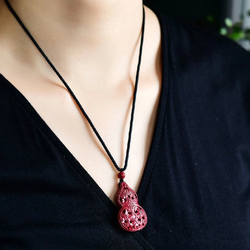 Cinnabar laughing Buddha Buddhist pendant showing joyful Buddha face carving on wine-red oval stone