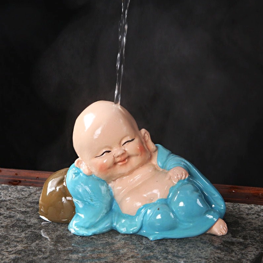 Laughing Buddha resin figurine paired with tea accessories on marble tea table, perfect feng shui décor piece