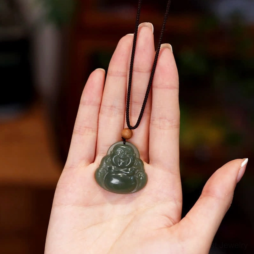 Laughing Buddha cyan jade pendant held in open palm, displaying detailed carved Buddha face and delicate black hanging cord