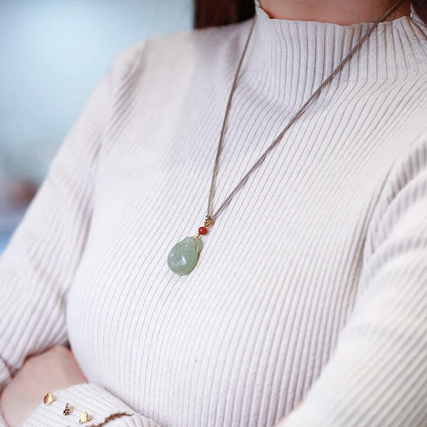 Buddhist jade pendant necklace worn on upper body with casual knit top, everyday spiritual jewelry styling