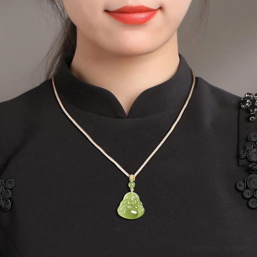 Woman wearing green jade laughing Buddha pendant necklace on upper chest in studio setting, showing how the Buddhist pendant sits when worn