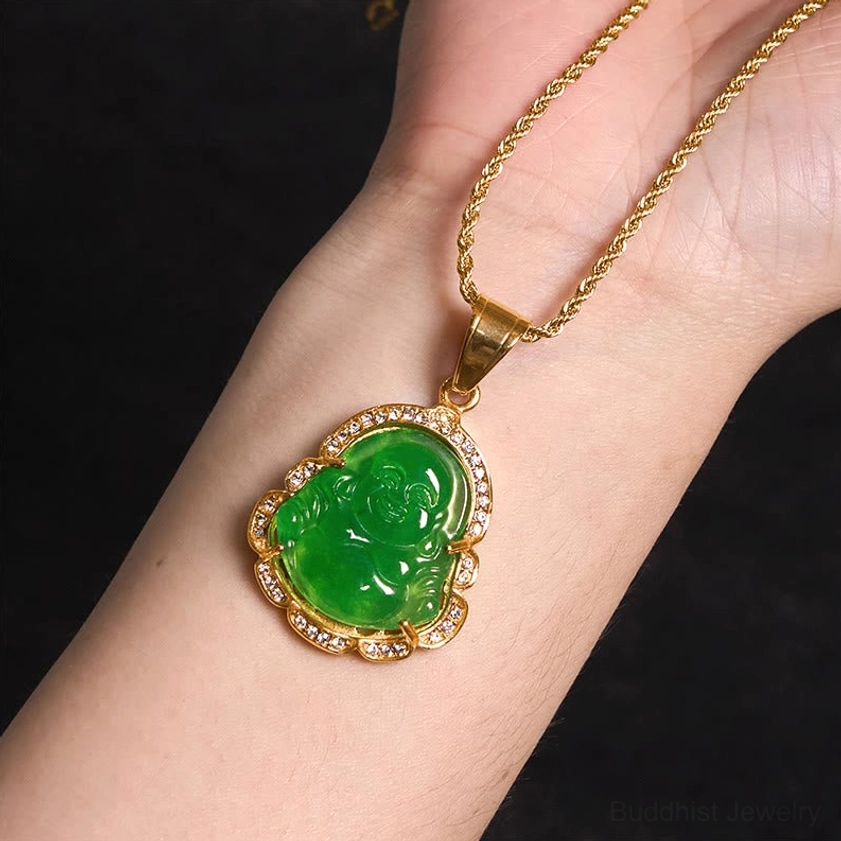 Laughing Buddha jade pendant worn on wrist showing gold twisted chain and rhinestone border detail against dark background