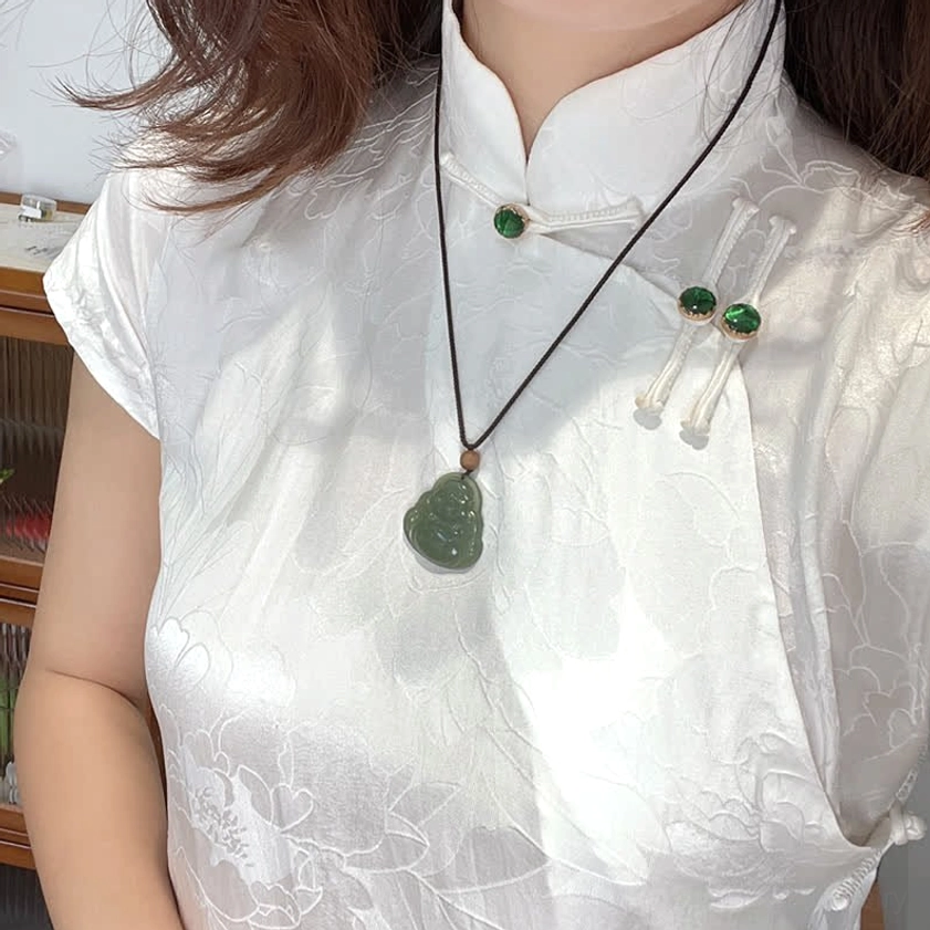 Laughing Buddha jade necklace styled with white cheongsam, showing long black cord with matching jade earrings for elegant cultural aesthetic
