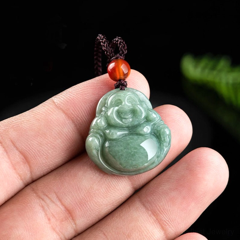 Laughing Buddha jade pendant held in hand showing detailed carving of smiling Maitreya Buddha with natural green jade stone