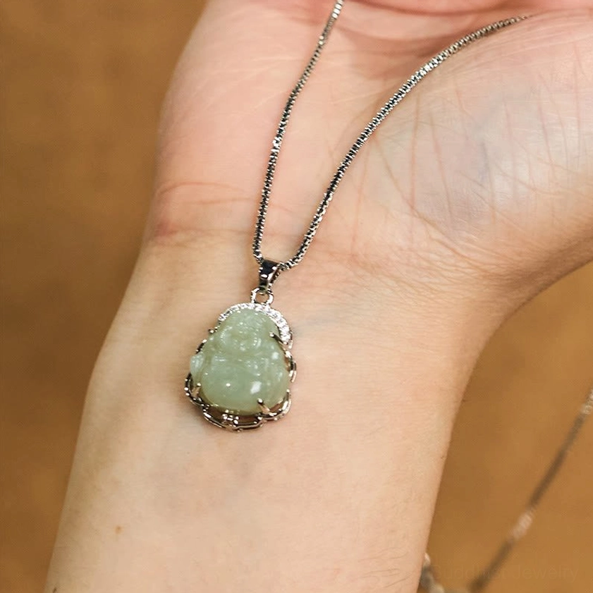 Pale green Hetian jade Laughing Buddha pendant worn as necklace on wrist in close-up view - spiritual Buddhist jewelry for daily wear and meditation practice