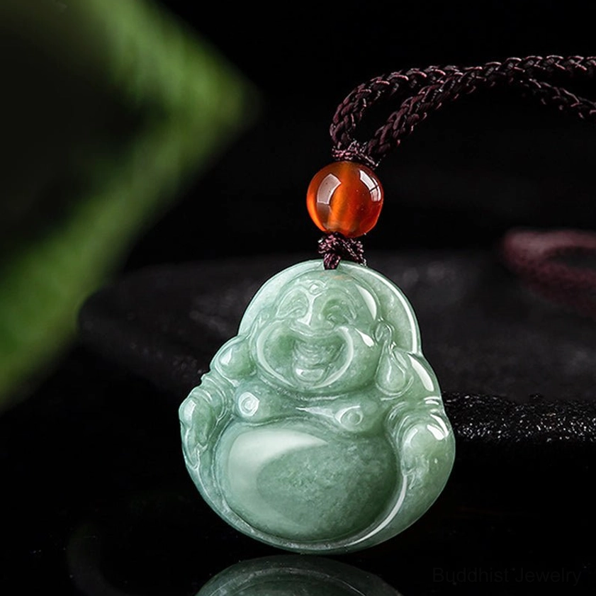 Side view of handcrafted cyan jade Buddha pendant with brown twisted cord and amber accent bead on dark background