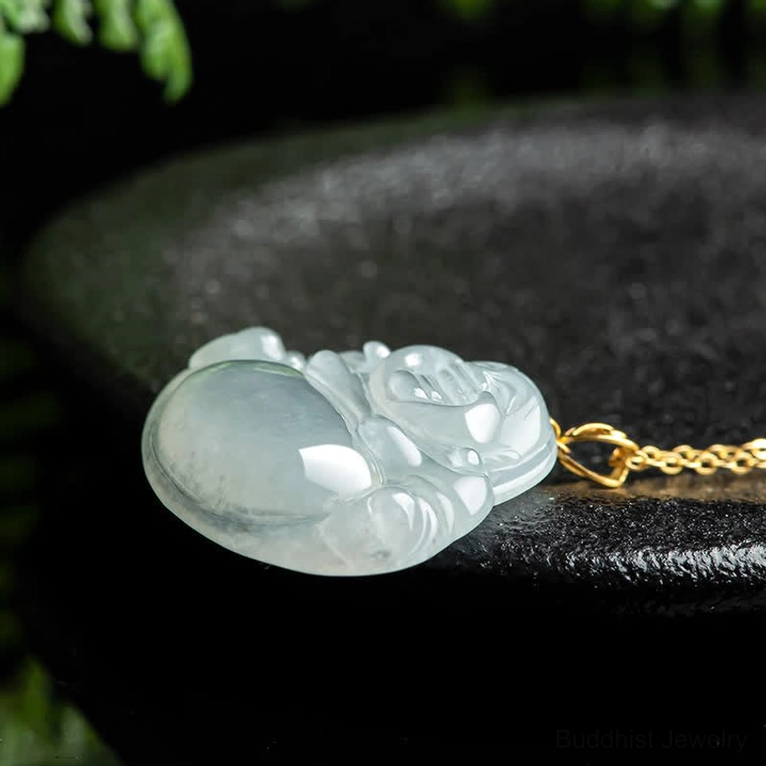 Side profile of natural jade Laughing Buddha pendant lying flat, showing smooth polished surface and gold chain attachment