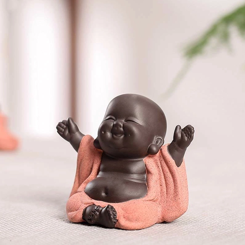 Laughing Buddha tea pet figurine left three-quarter view with cheerful expression and raised arms, desktop meditation decor