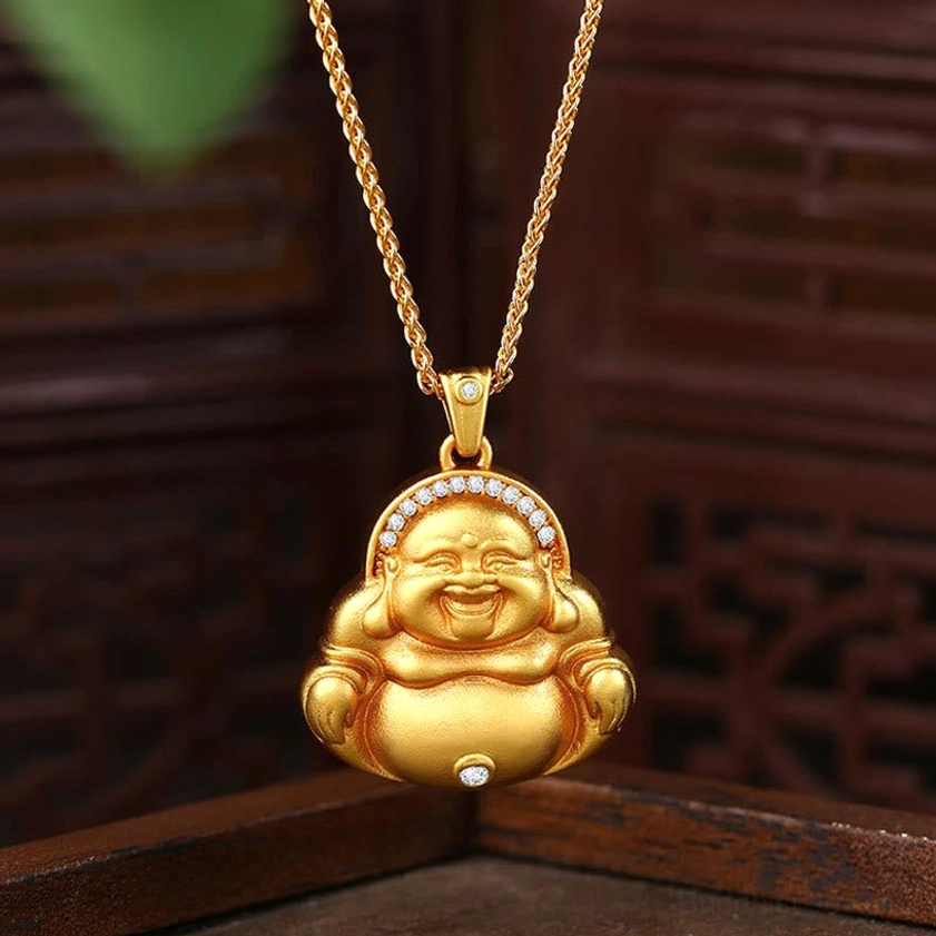 Laughing Buddha gold pendant necklace front view with zircon inlays and Fu character carving on traditional wooden background