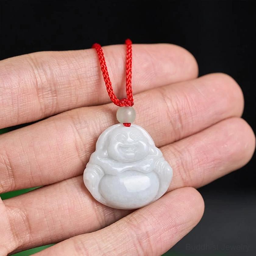 Hand-held size reference of jade Buddha pendant on finger showing proportions and light grey natural stone color