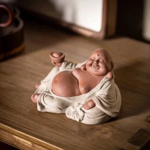 Laughing Buddha purple clay statue holding gold ingot, front three-quarter view on wooden tea table, beige robe with serene smile