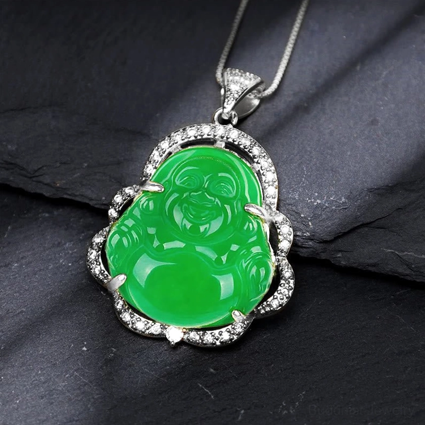 Silver-toned laughing Buddha green jade pendant necklace with zirconia flower frame, angled view on dark slate