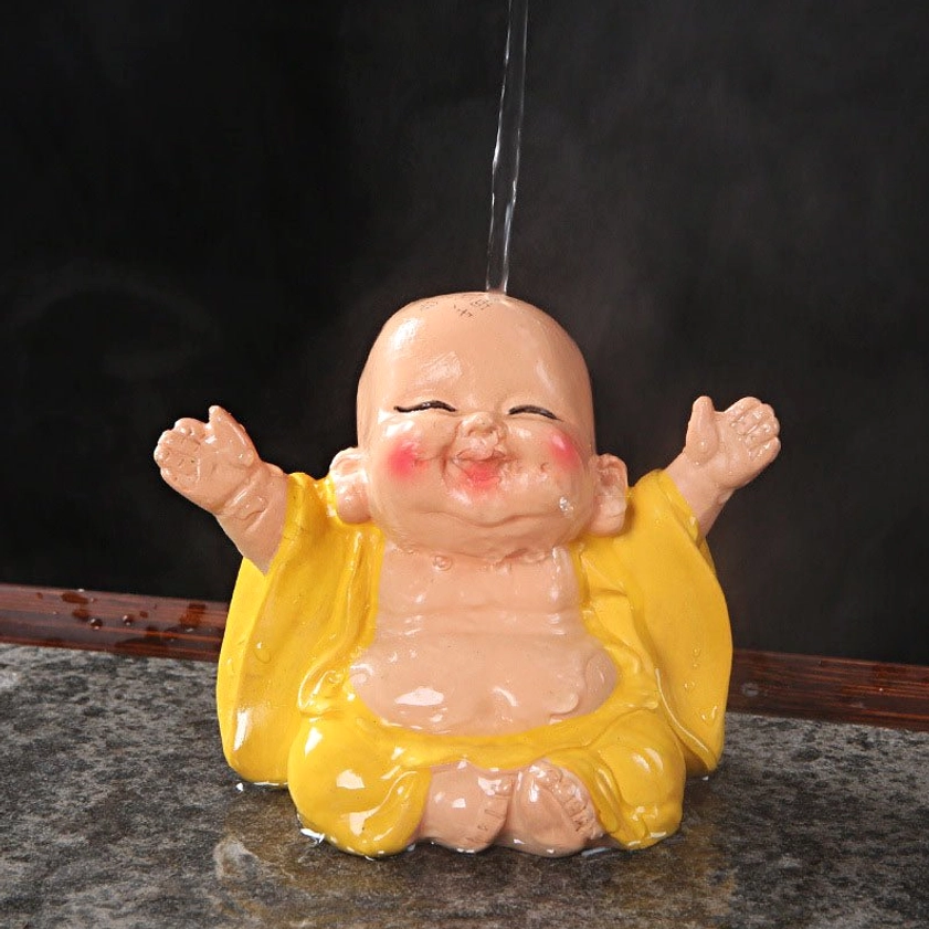 Color-changing laughing Buddha tea pet with steaming hot water on marble tea table, yellow robe transforming in real-time