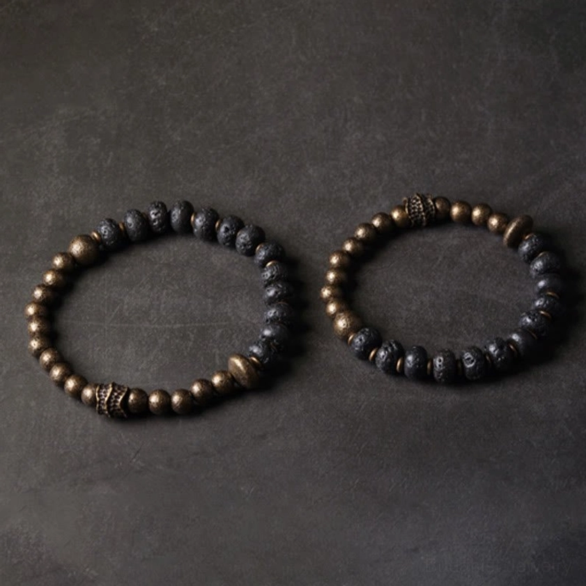 Two matching lava rock and copper Buddhist bracelets displayed together showing identical design