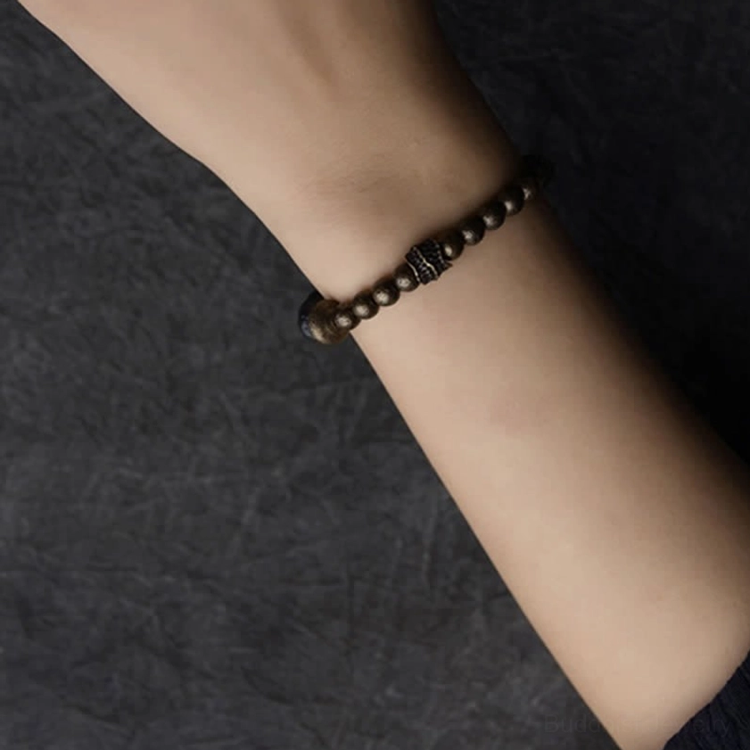 Single strand lava rock beaded balance bracelet side view on wrist with mixed dark and brass tones